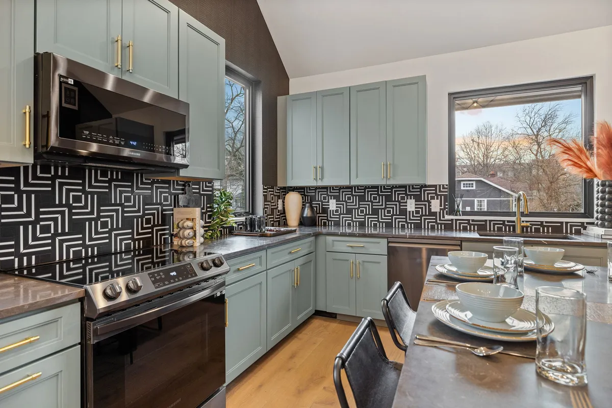 This image shows a modern kitchen interior with sleek cabinets, a stylish backsplash, a kitchen island, and up-to-date appliances. The atmosphere is fresh and contemporary, hinting at both professional management and attention to detail. The scene suggests starter kitchen amenities and a clean, inviting space for guests.