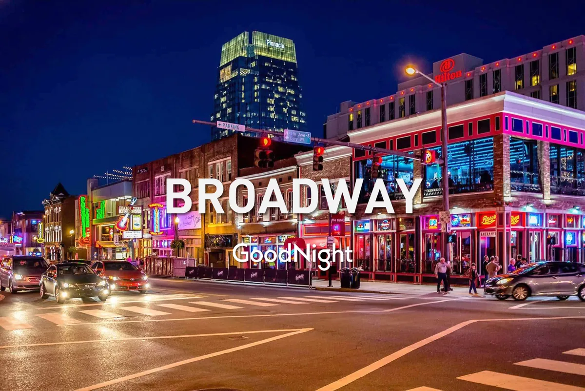 A vibrant exterior scene of a bustling street lined with neon signs, people walking, and high-rise buildings in the background. The image captures the excitement and energy of downtown Nashville, inviting exploration of its famous nightlife and music venues.