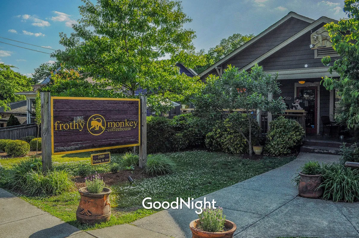 The exterior of Frothy Monkey Coffeehouse, featuring well-maintained landscaping, inviting signage, and a cozy building facade. The photo captures a welcoming spot perfect for walking to with your pet and soaking up the neighborhood's community vibe.