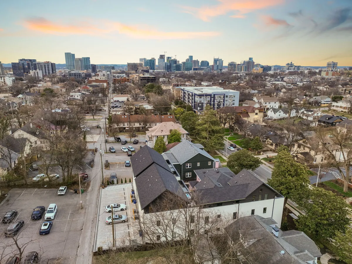 A view of the property’s exterior parking area with the city skyline and residential buildings in the background. The scene is serene and inviting, highlighting the accessibility and security of parking for guests.